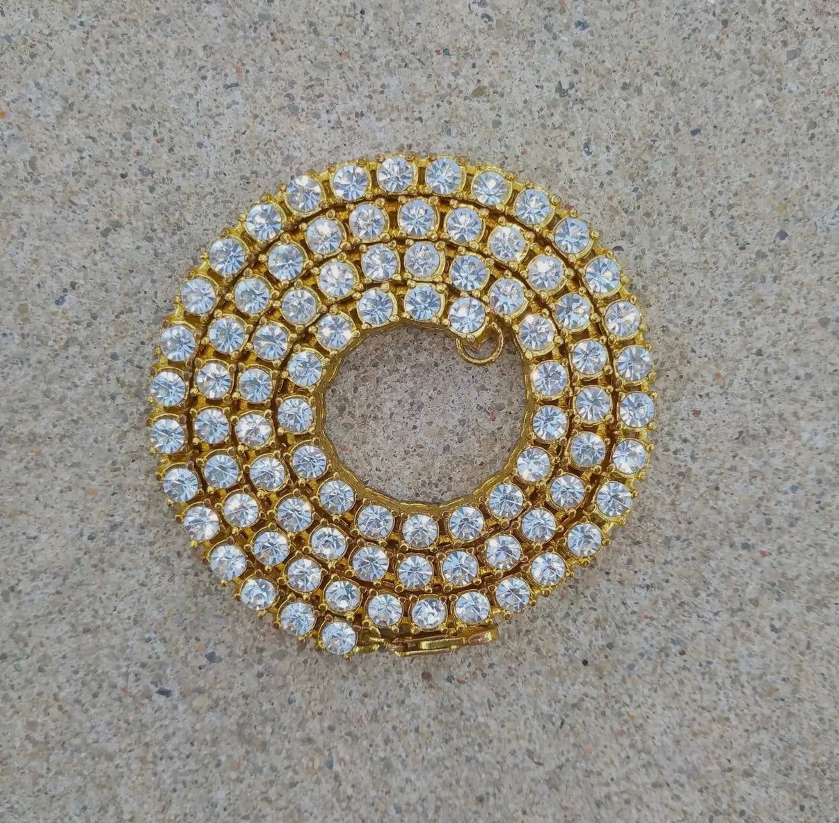 "Iced Out Tennis Kette aus Edelstahl in Gold – Luxus-Schmuck für Hip-Hop-Stil, Streetwear und exklusive Looks. Jetzt online entdecken und bestellen."

"Edle goldene Tennis Kette Iced Out – Glänzendes Design aus Edelstahl mit Strasssteinen, die jedem Outfit das gewisse Etwas verleihen. Perfekt für Herren und Damen."